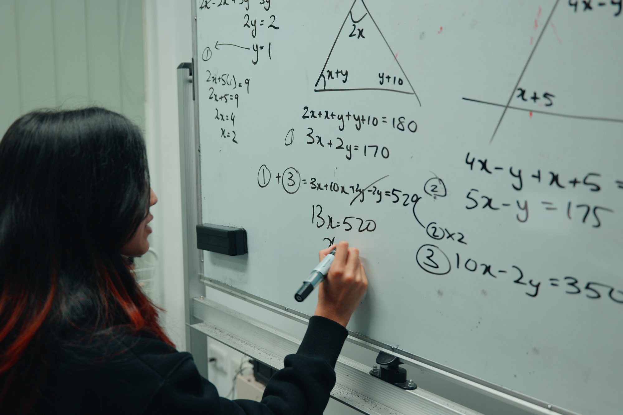 A Spartan Tuition tutor working through algebra on the whiteboard