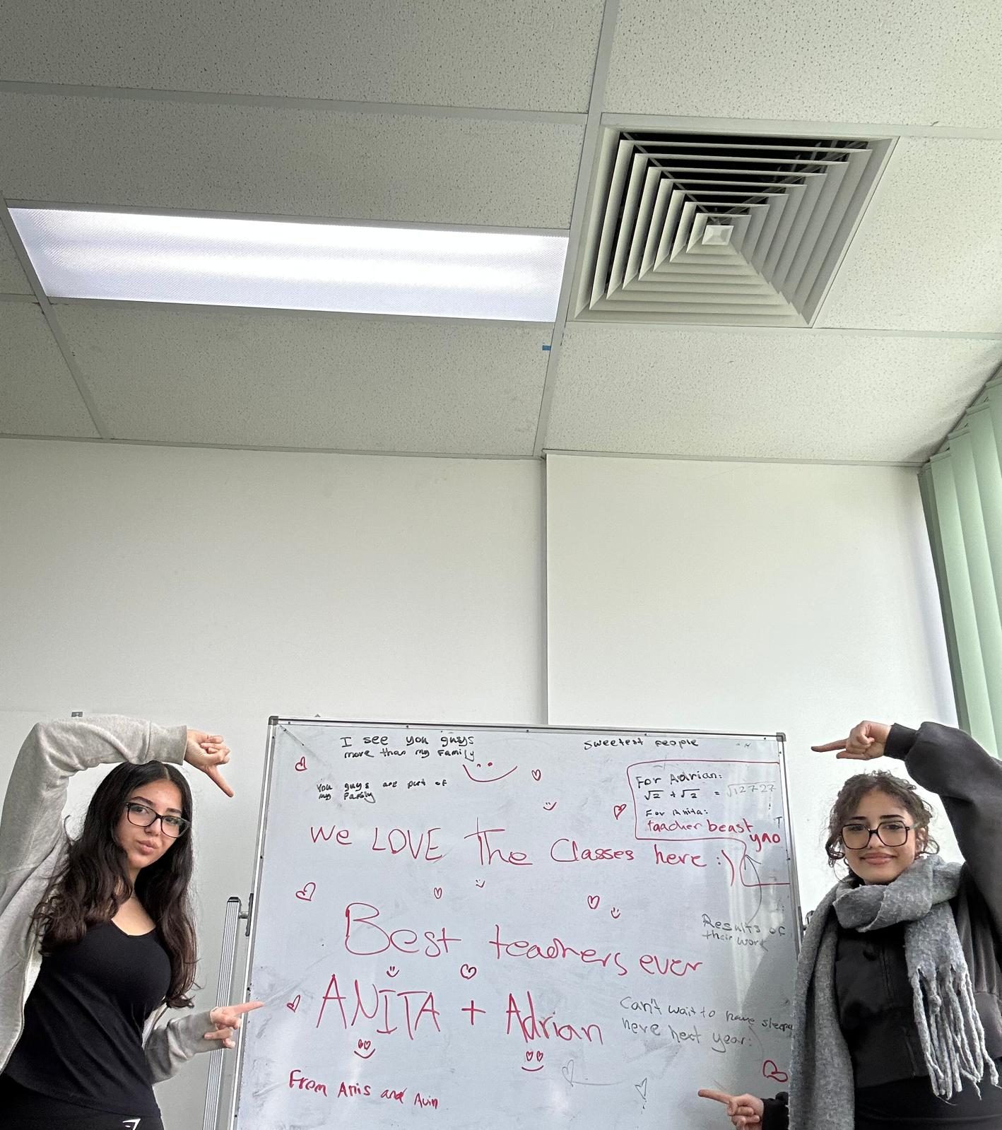 Students pointing to a thank-you message they wrote on the whiteboard